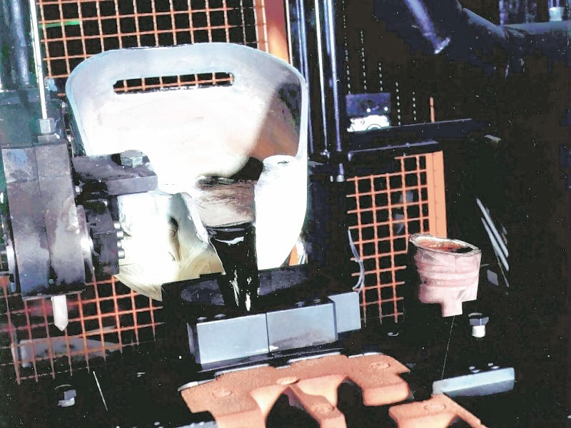 Bild 2: An einem Gießmanipulator angebrachter Gießlöffel beim Eingießen der Schmelze, Foto: Fa. Fill GmbH