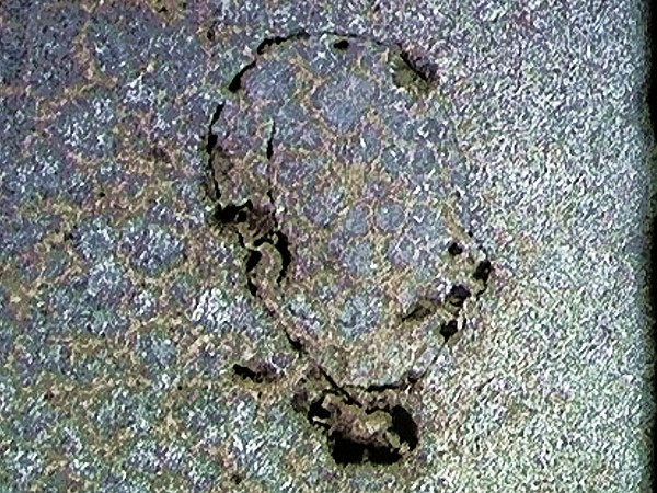 Bild 1: Spritzkugel im metallografischen Schliff, umgeben von einer Oxidhaut, Quelle: IPIS-Gussfehleratlas